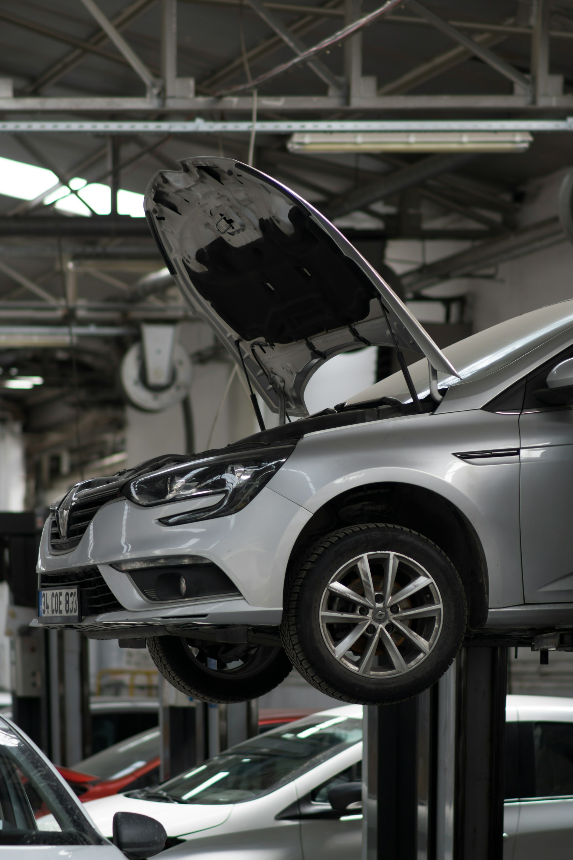 a car lifted up with hydraulic lift with a car bonnet open